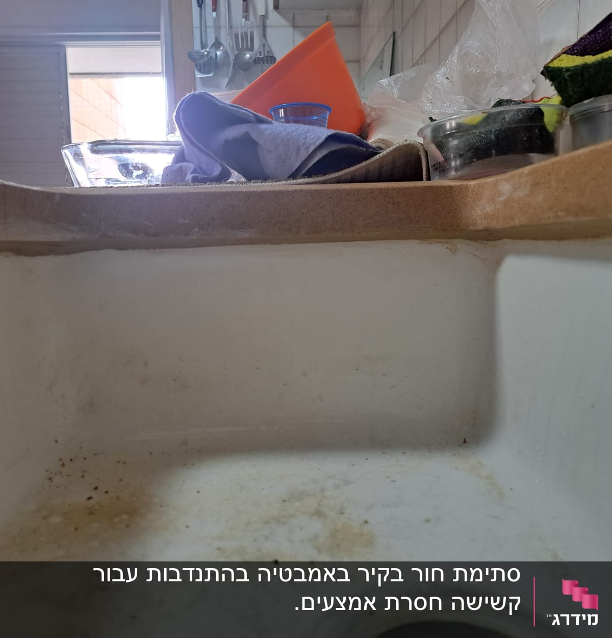 כיור מלוכלך עם כלים וספוגים על השיש